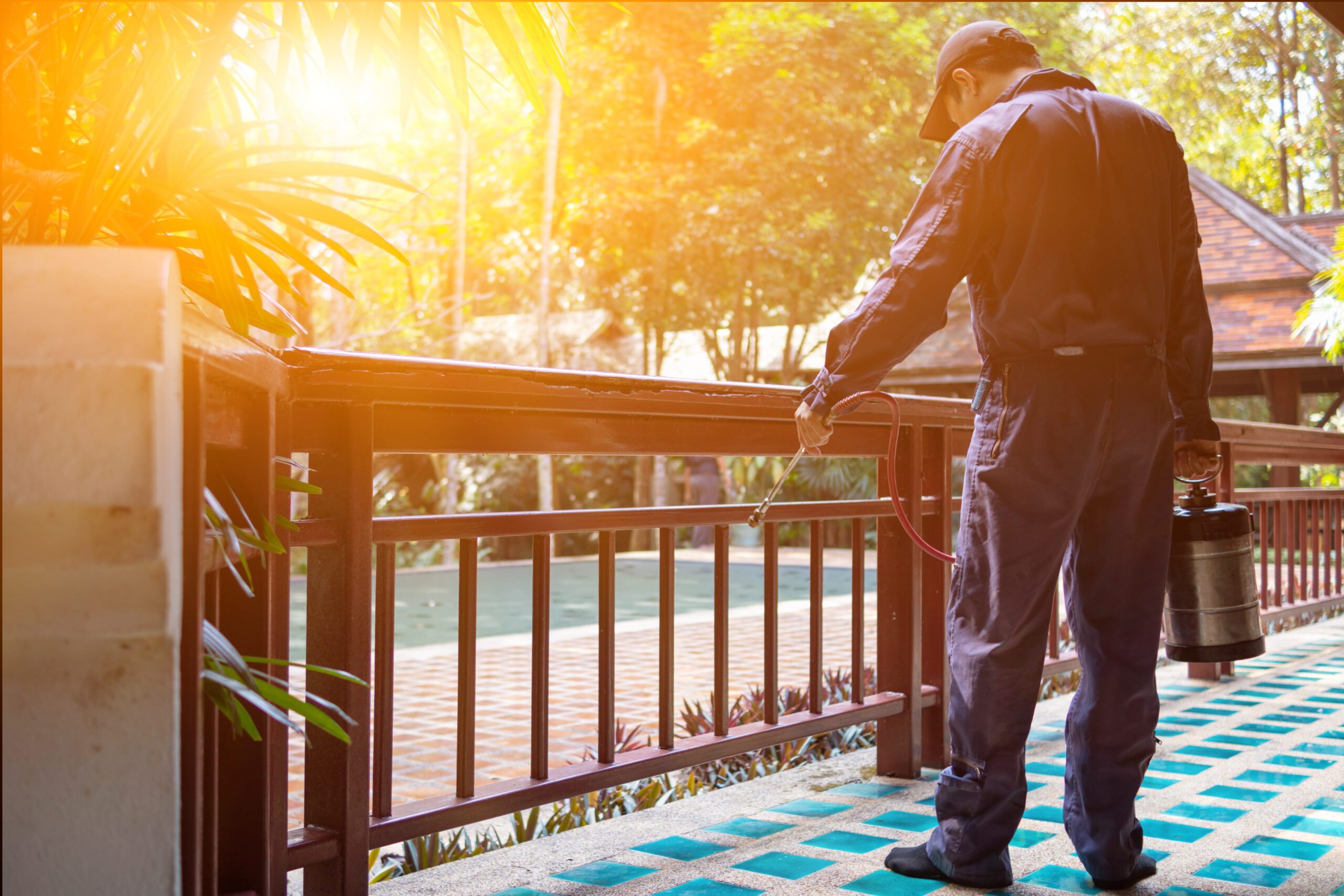 Local pest control exterminator performing a pest treatment on a deck
