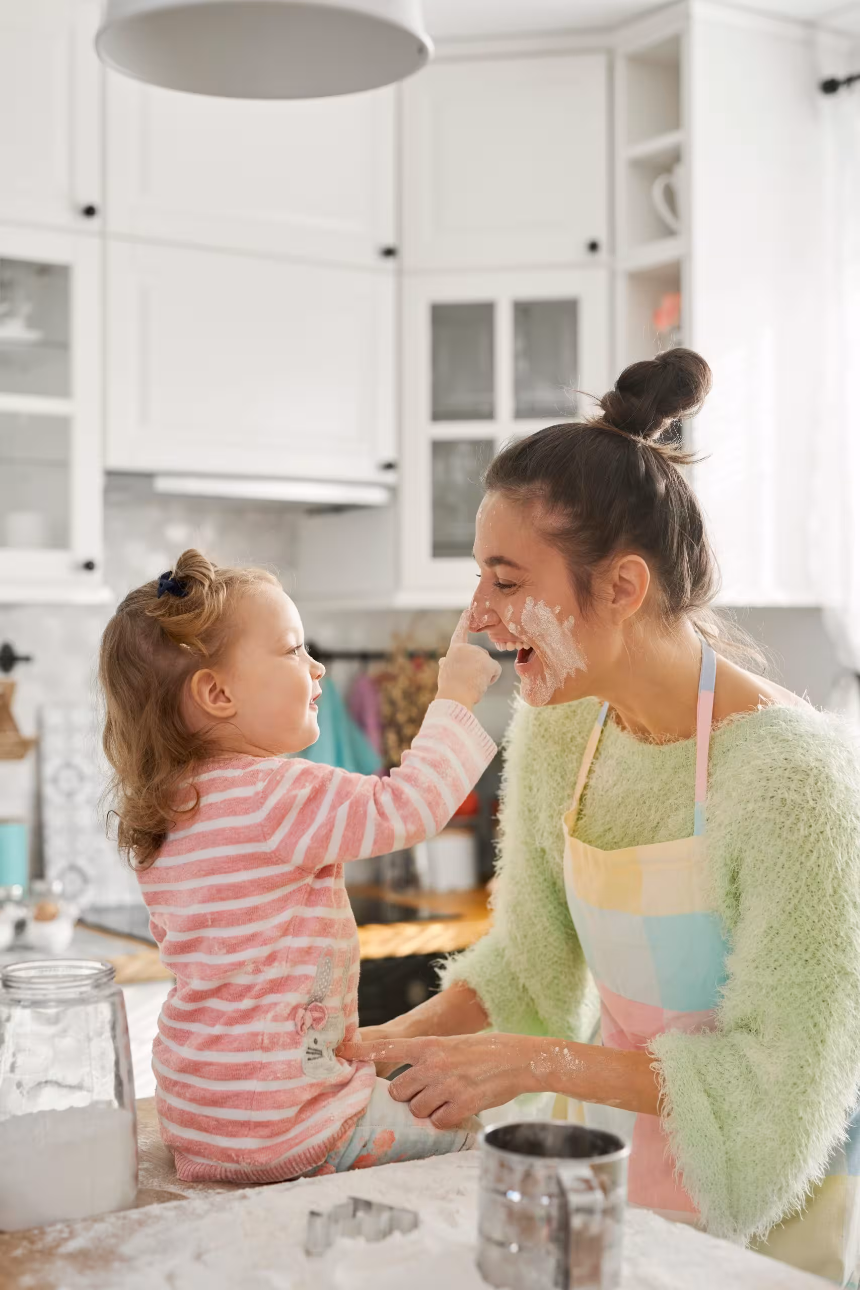 mother and daughter playing with flour in kitchen